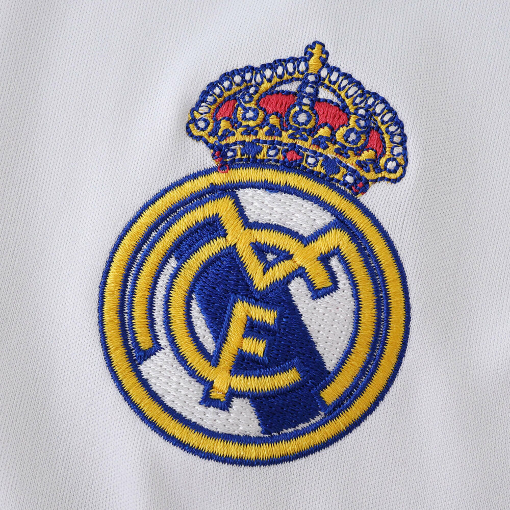 Embroidered Real Madrid crest on white fabric, featured on the 2025/26 home fan jersey.