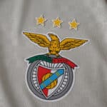 Close-up of SL Benfica crest with three stars on the 2025/26 away fan version jersey fabric.