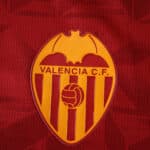 Valencia C.F. crest on the 2025/26 away fan jersey, featuring a red and gold design.