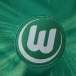 Close-up of the VfL Wolfsburg home jersey 2025/26 fan version, showing the embroidered club crest.
