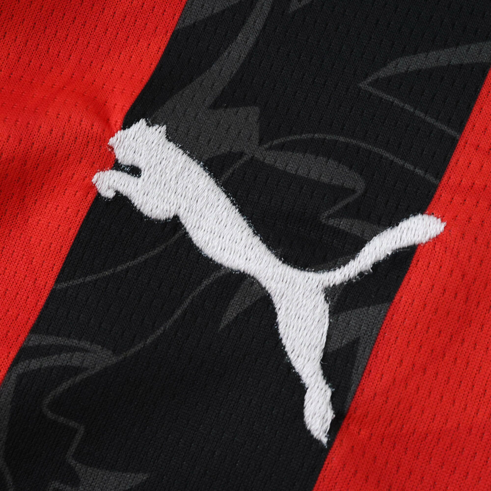 Close-up of the Puma logo on the AC Milan 2025/26 Home Fan Version jersey, featuring red and black stripes.