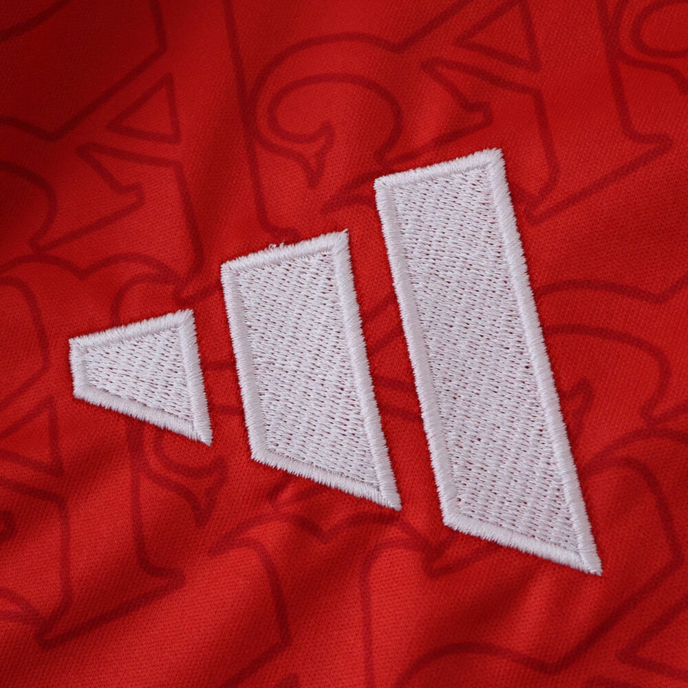 Close-up of the white Adidas logo on the red 2025/26 Arsenal Home fan version jersey.