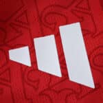 Close-up of the Adidas logo on the red Arsenal Home 2025/26 Player Version jersey.