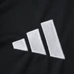 White Adidas logo embroidered on the black fabric of the Aston Villa Away 2025/26 Fan Version jersey.