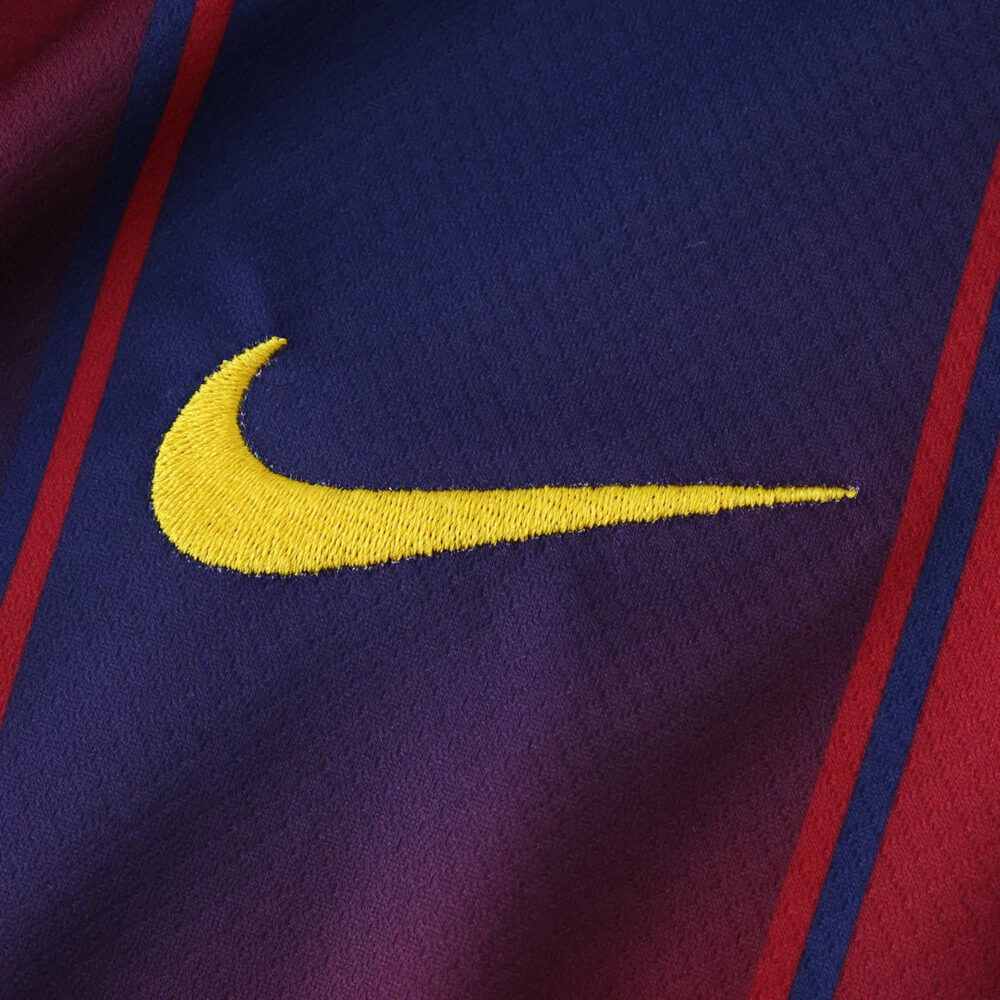 Close-up of the yellow Nike logo on the Barcelona Home 2025/26 Fan Version jersey fabric.