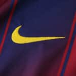 Close-up of the yellow Nike logo on the Barcelona Home 2025/26 Fan Version jersey fabric.
