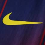 Close-up of the yellow Nike logo on the 2025/26 Barcelona Home Player Version jersey fabric.