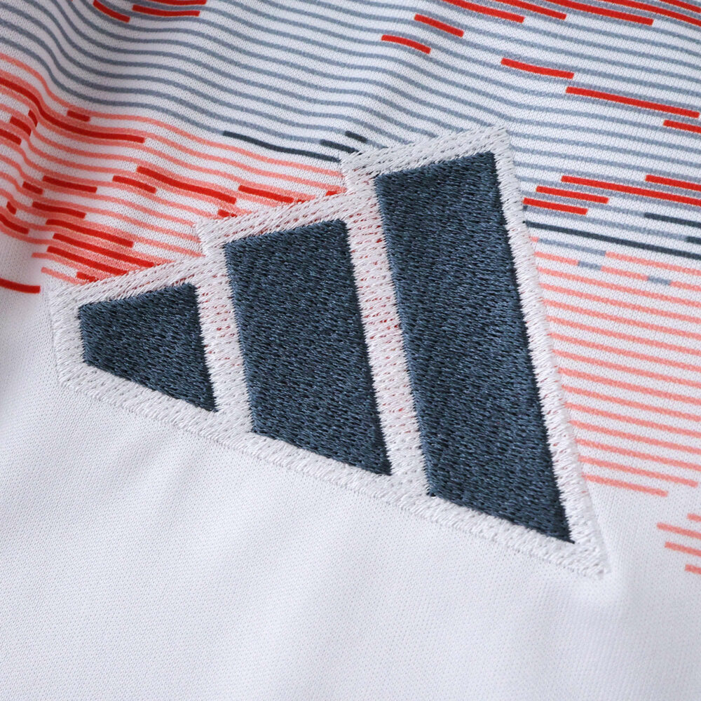 Close-up of the Adidas logo on the Bayern Munich 2025/26 Away Fan Version jersey, white with red and black details.