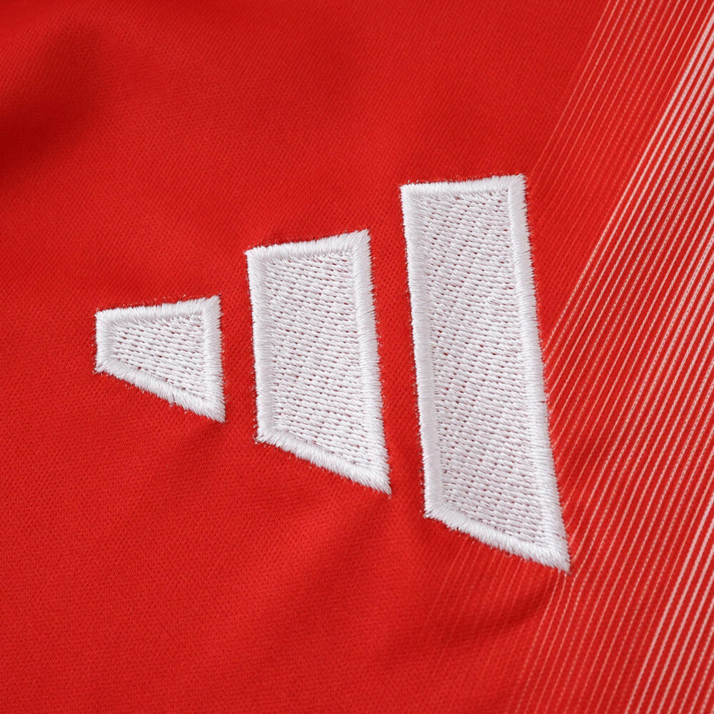 Close-up of the Bayern Munich 2025/26 Home Fan Version jersey featuring the Adidas logo on red fabric.