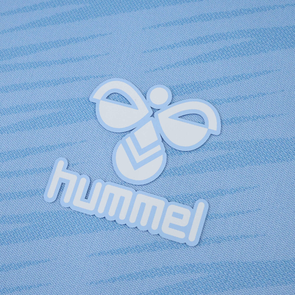 Close-up of the Hummel logo on the light blue Celta Vigo 2025/26 home fan jersey.