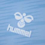 Close-up of the Hummel logo on the light blue Celta Vigo 2025/26 home fan jersey.
