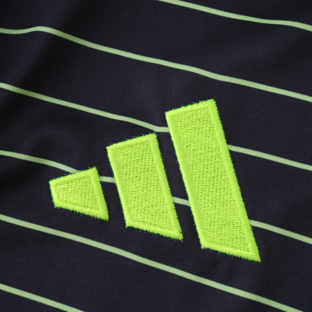 Close-up of lime green Adidas logo on the Celtic Away 2025/26 Fan Version jersey with thin green stripes.