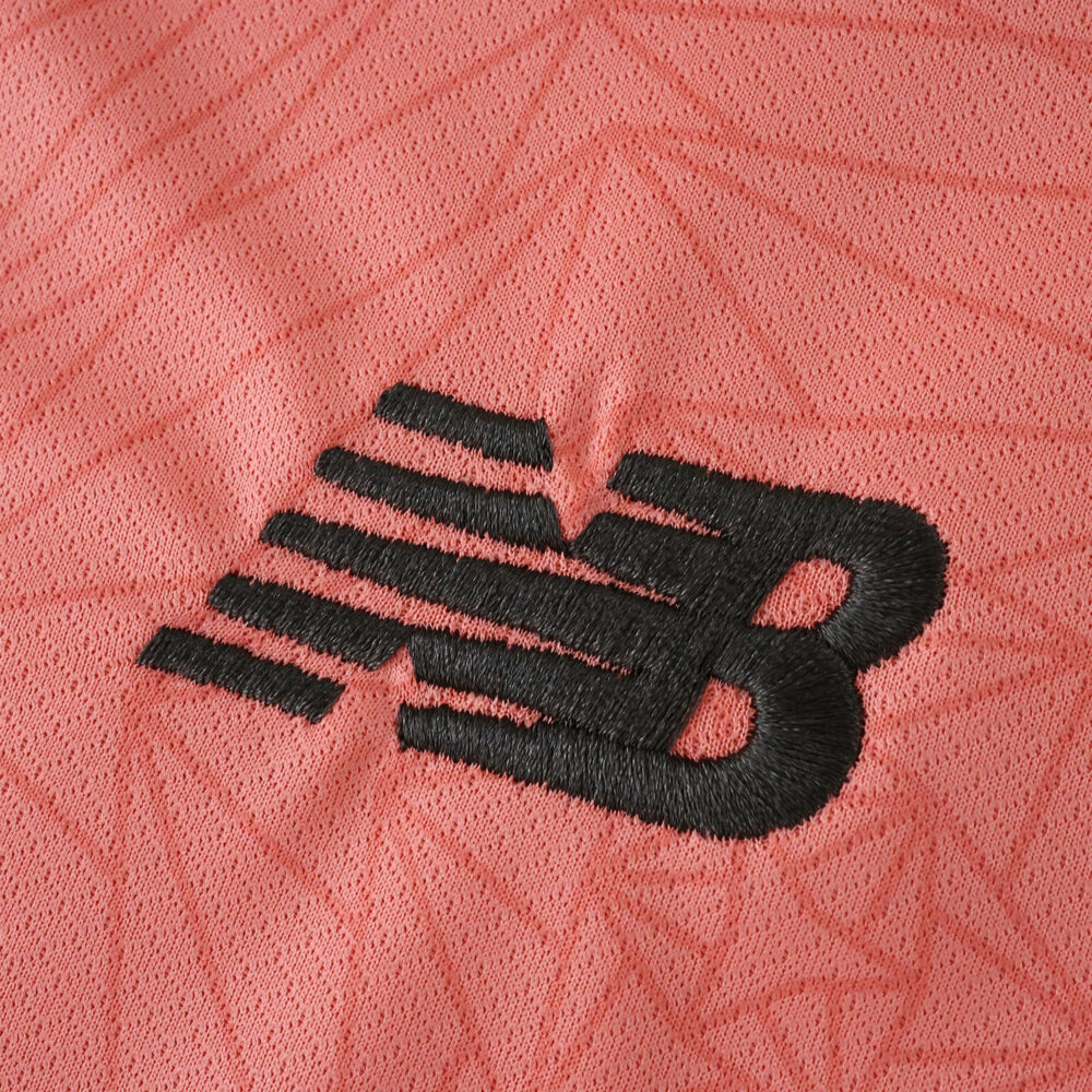 Close-up of the black New Balance logo on the pink FC Porto Away 2025/26 Fan Version jersey fabric.