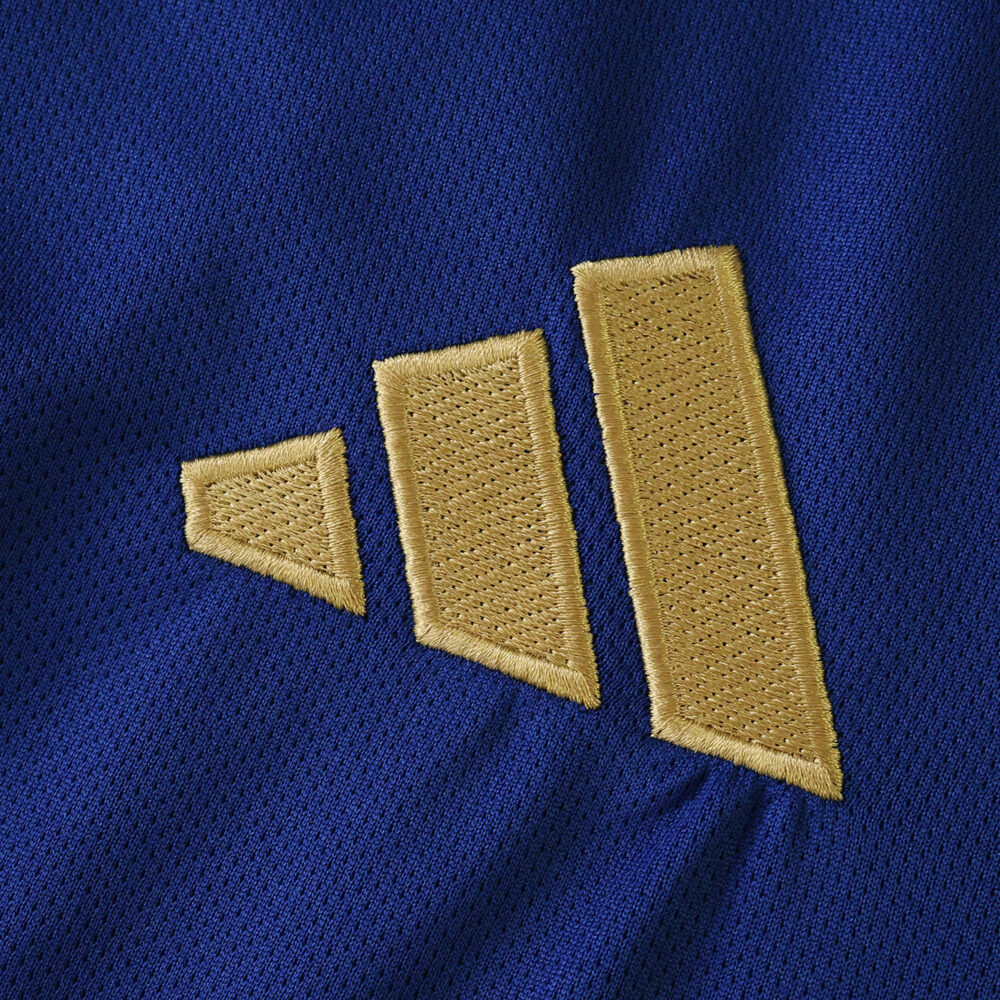 Close-up of gold Adidas logo on blue Hamburger SV Away 2025/26 Fan Version jersey fabric.