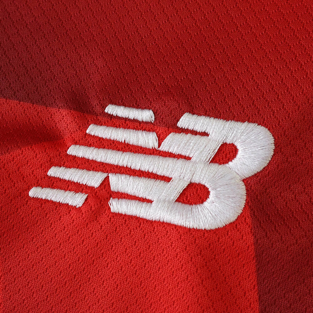 Close-up of New Balance logo on the red Lille LOSC 2025/26 Home Fan Version jersey.