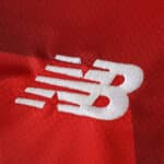 Close-up of New Balance logo on the red Lille LOSC 2025/26 Home Fan Version jersey.
