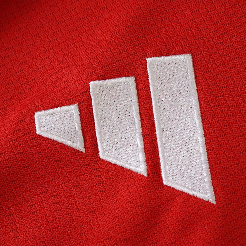 Close-up of the white Adidas logo on red fabric from Liverpool Home 2025/26 Fan Version jersey.