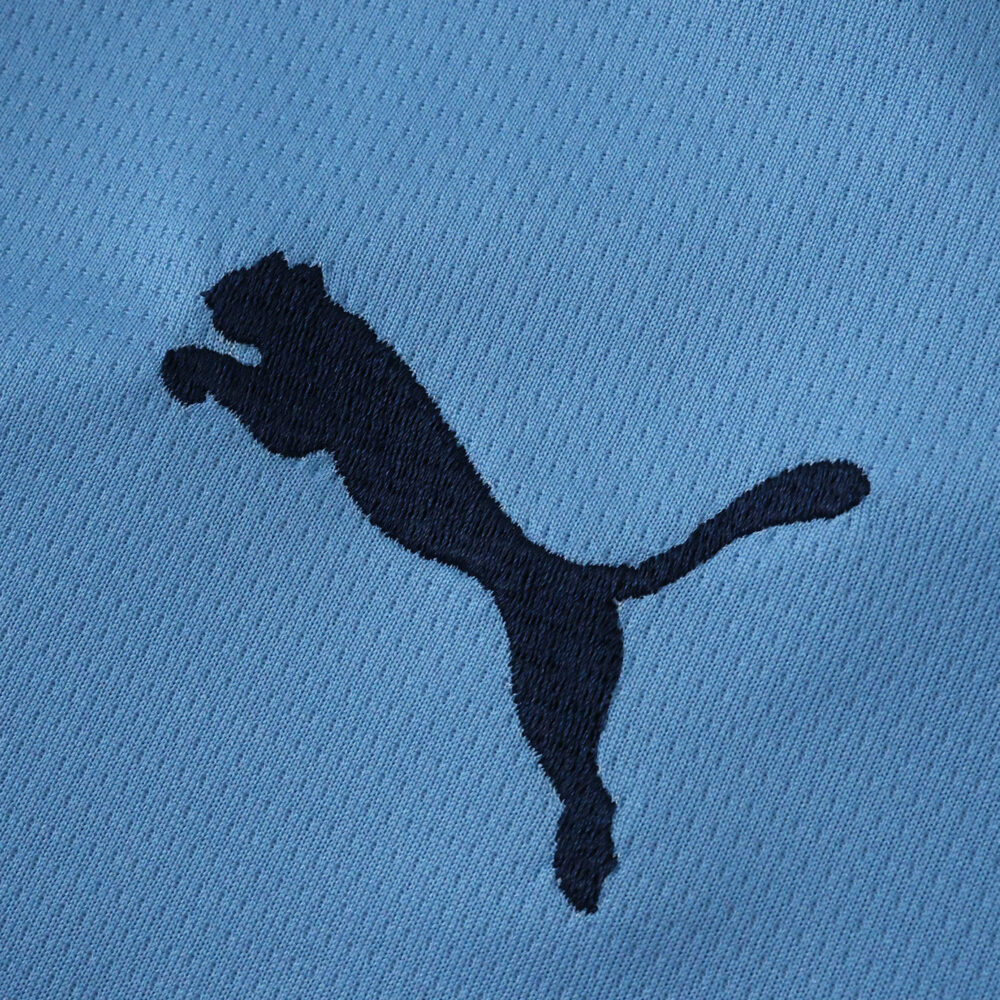 Close-up of the black Puma logo on the Manchester City 2025/26 Home Fan Version jersey's blue fabric.