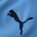 Close-up of the black Puma logo on the sky blue 2025/26 Manchester City Home Player Version jersey.