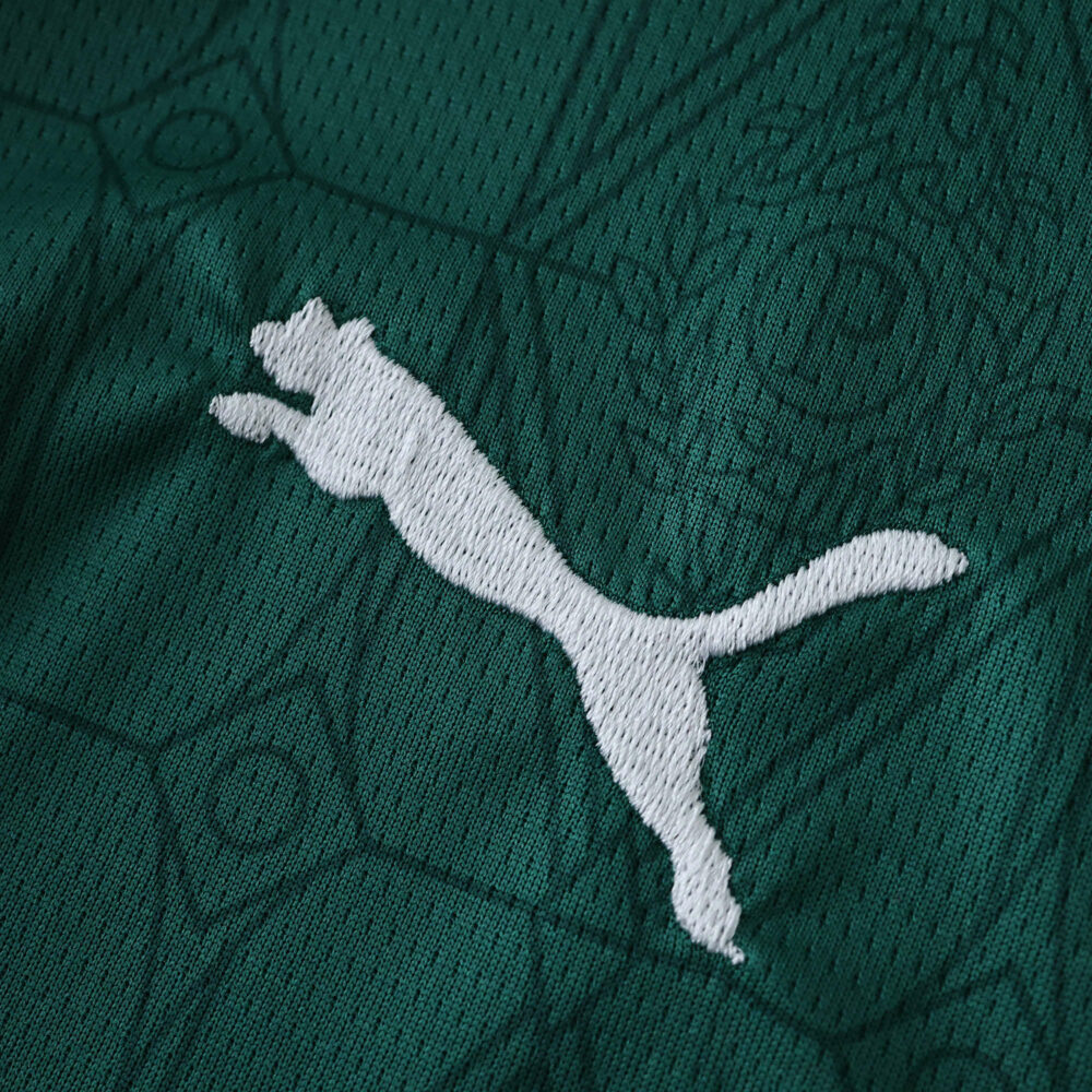 Close-up of the Puma logo embroidered on the green Palmeiras 2025/26 home fan jersey.