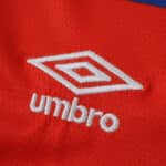 Close-up of white Umbro logo embroidered on the red Rangers Away 2025/26 Fan Version jersey fabric.