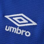 Close-up of the Umbro logo embroidered on the blue Rangers Home 2025/26 Fan Version jersey fabric.