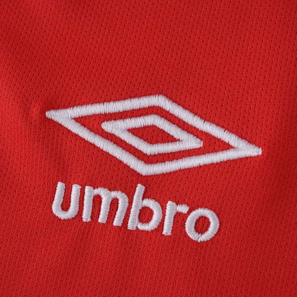 Close-up of the white Umbro logo on the red Rangers Third 2025/26 Fan Version jersey fabric.