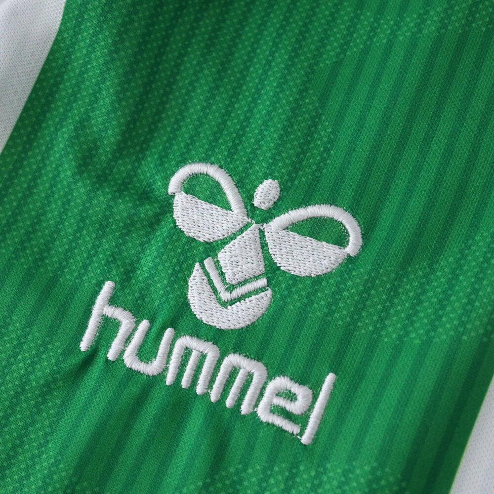Close-up of the Hummel logo embroidered on the green Real Betis Home 2025/26 Fan Version jersey fabric.