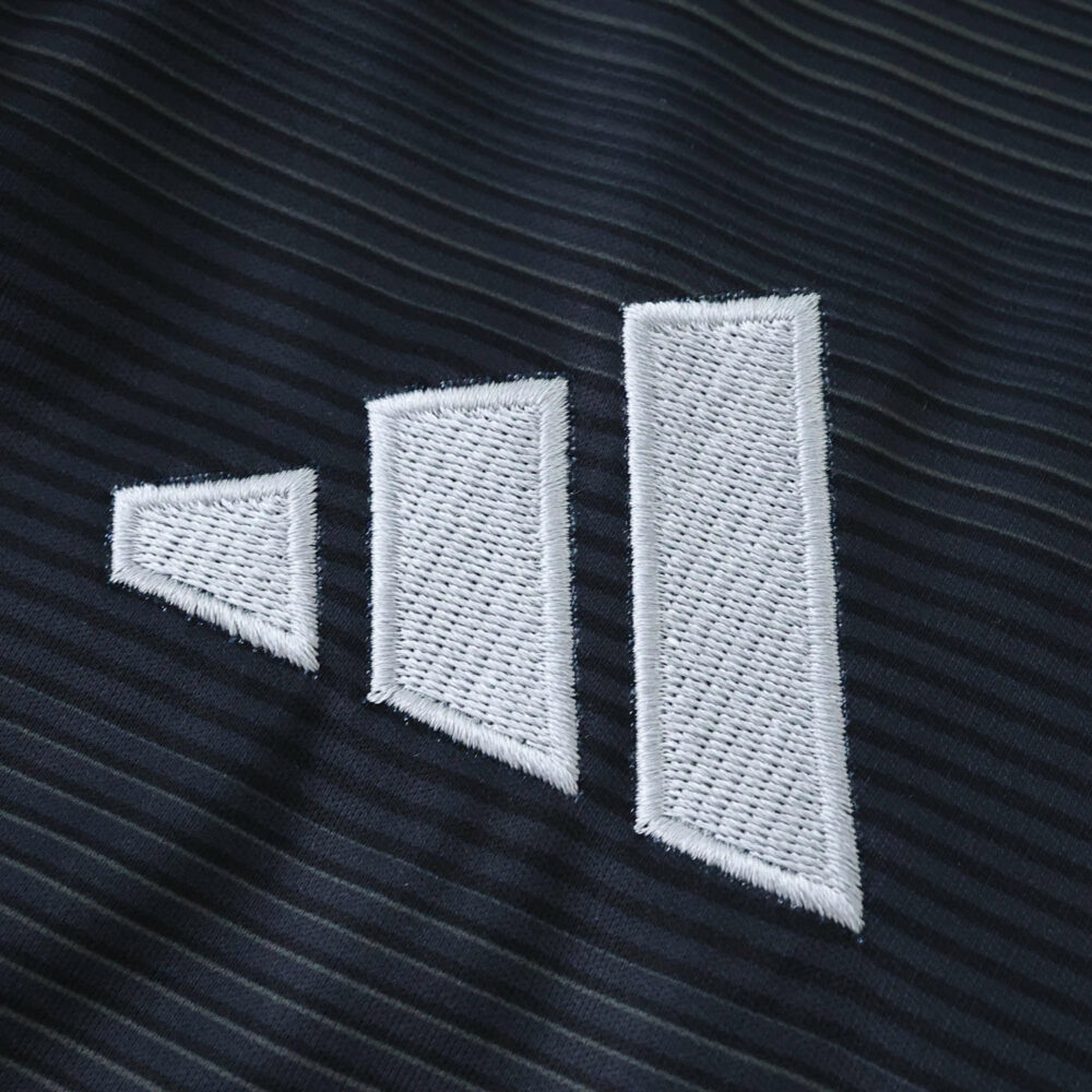 Close-up of the Real Madrid 2025/26 away fan jersey fabric with a white geometric Adidas logo.