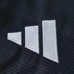 Close-up of the Real Madrid 2025/26 away fan jersey fabric with a white geometric Adidas logo.