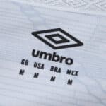 Close-up of Santos FC 2025/26 home jersey fabric showing Umbro logo and size details in black text.