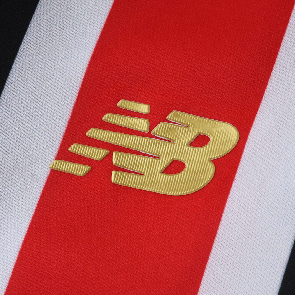 Close-up of the New Balance logo on the São Paulo Away 2025/26 Fan Version jersey with red, white, and black stripes.