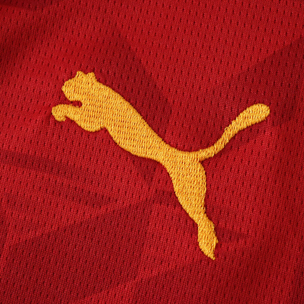 Close-up of the yellow Puma logo on the red Valencia Away 2025/26 Fan Version jersey.