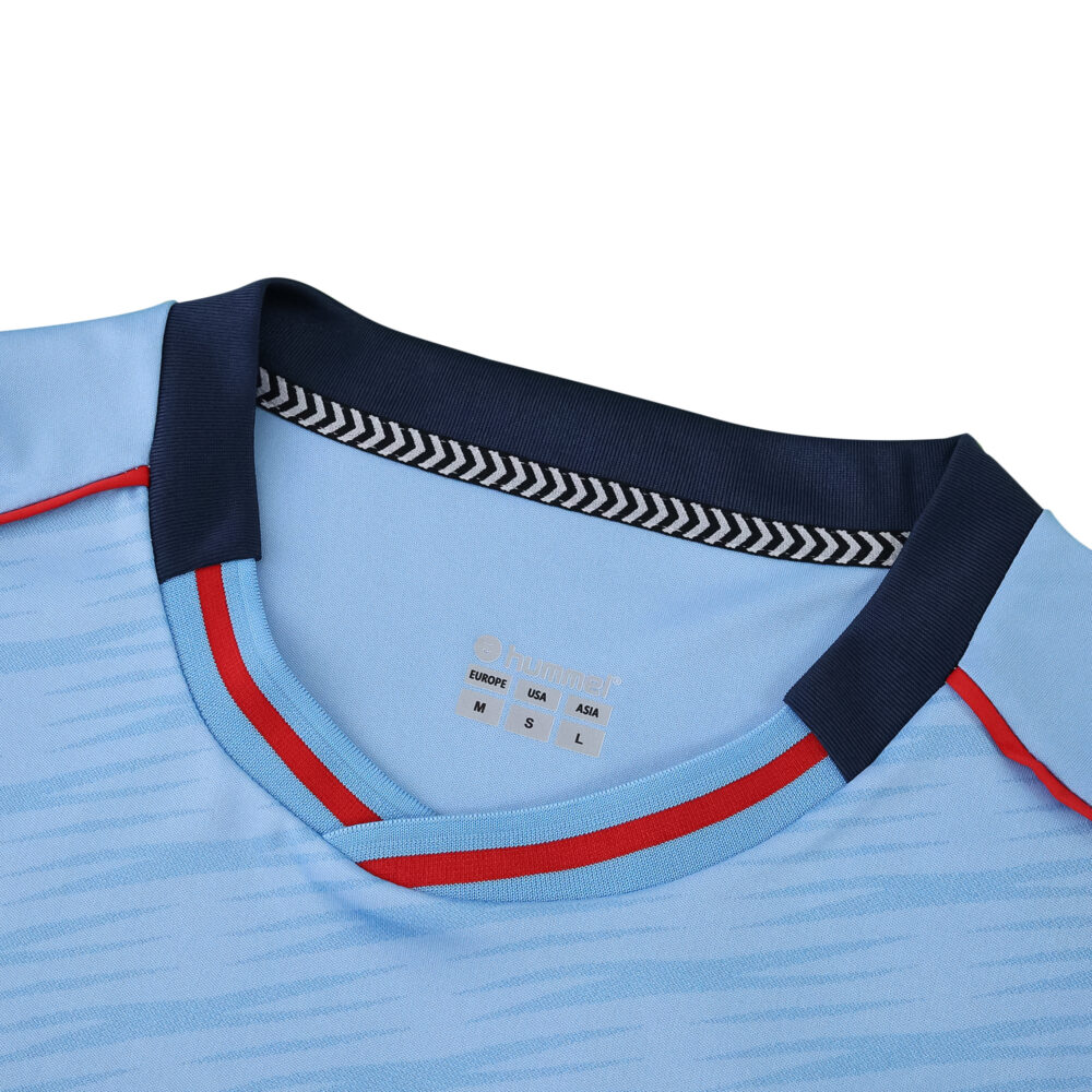 Close-up of Celta Vigo 2025/26 home fan jersey collar, light blue with navy and red trim.