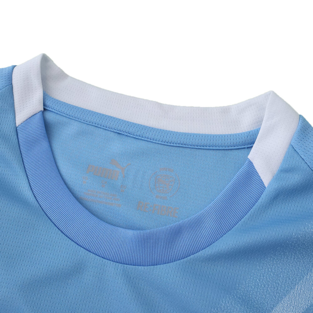 Close-up of Manchester City 2025/26 home fan jersey collar in light blue with white trim.