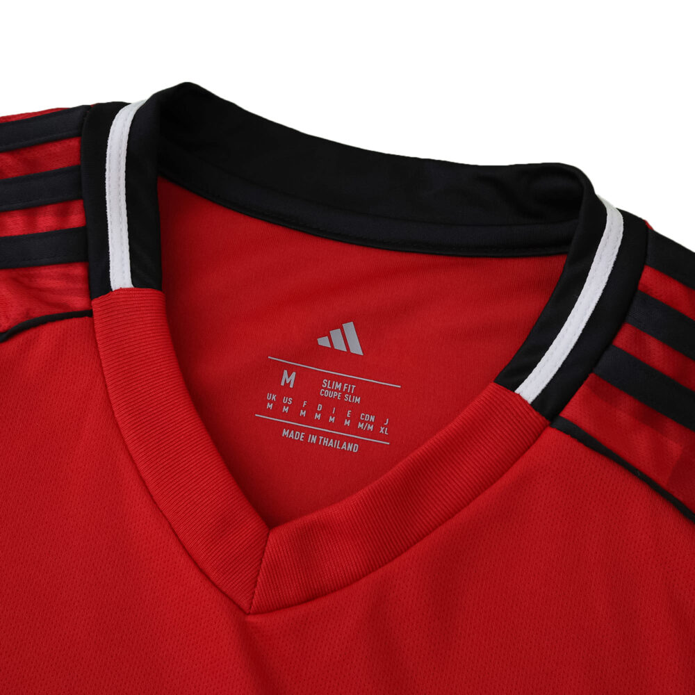 Close-up of Manchester United 2025/26 home fan jersey collar, featuring red fabric with black and white trim.