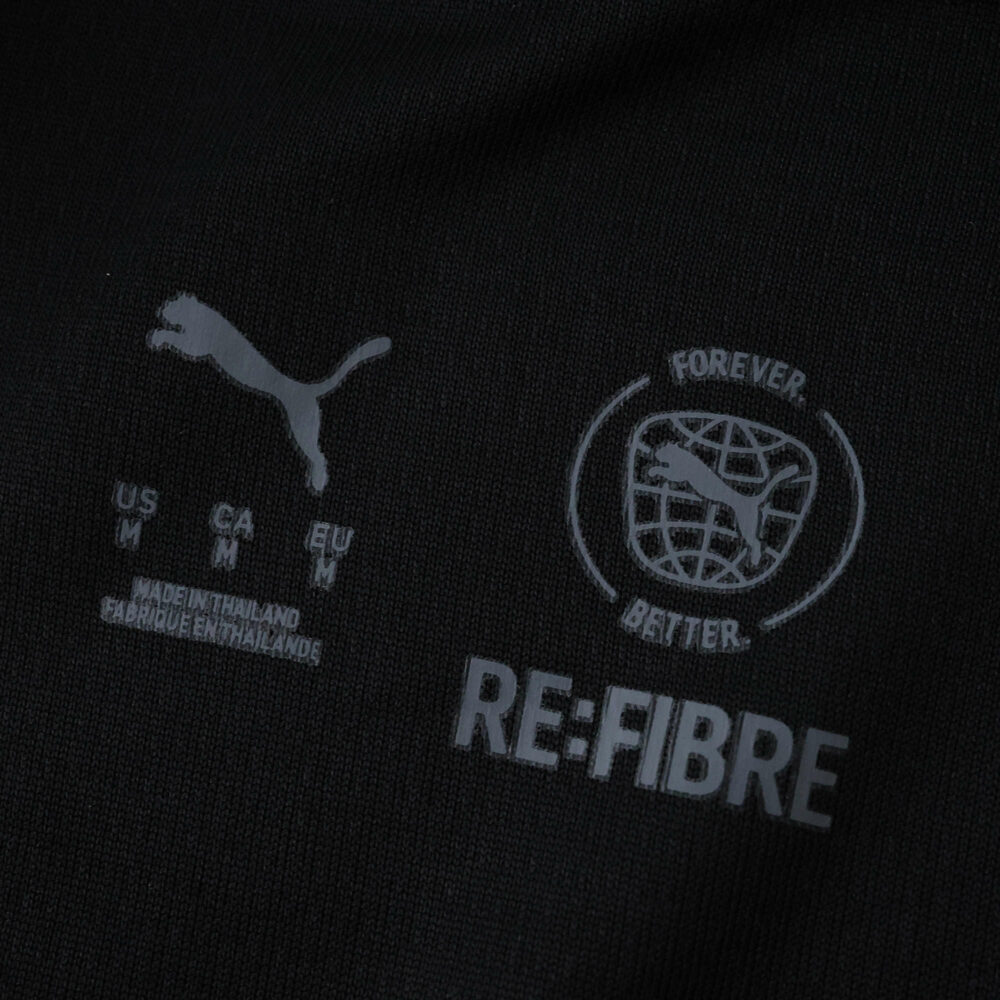 Close-up of AC Milan 2025/26 Fan Home Jersey fabric showing Puma and RE:FIBRE sustainability logos.