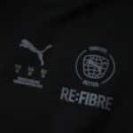 Close-up of AC Milan 2025/26 Fan Home Jersey fabric showing Puma and RE:FIBRE sustainability logos.