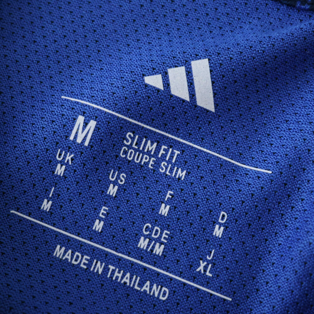 Close-up of Arsenal Away 2025/26 Player Version jersey label, showing size and fit details on blue fabric.