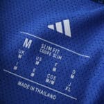 Close-up of Arsenal Away 2025/26 Player Version jersey label, showing size and fit details on blue fabric.