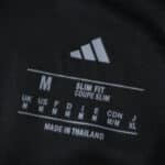 Close-up of Aston Villa Away 2025/26 Fan Version shirt tag displaying size M and slim fit details.