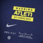 Close-up of Atlético Madrid Away 2025/26 Fan Version jersey details, featuring "WARNING ATLETI NOT TURNING BACK" text.