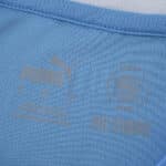 Close-up of Manchester City 2025/26 Home Fan Version collar featuring Puma logo and RE:FIBRE label.