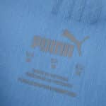 Close-up of Puma logo and care label on the Manchester City Home 2025/26 Player Version jersey fabric.