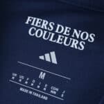 Close-up of Olympique Lyonnais Away 2025/26 Fan Version shirt tag with size and "Fiers de nos couleurs" text.