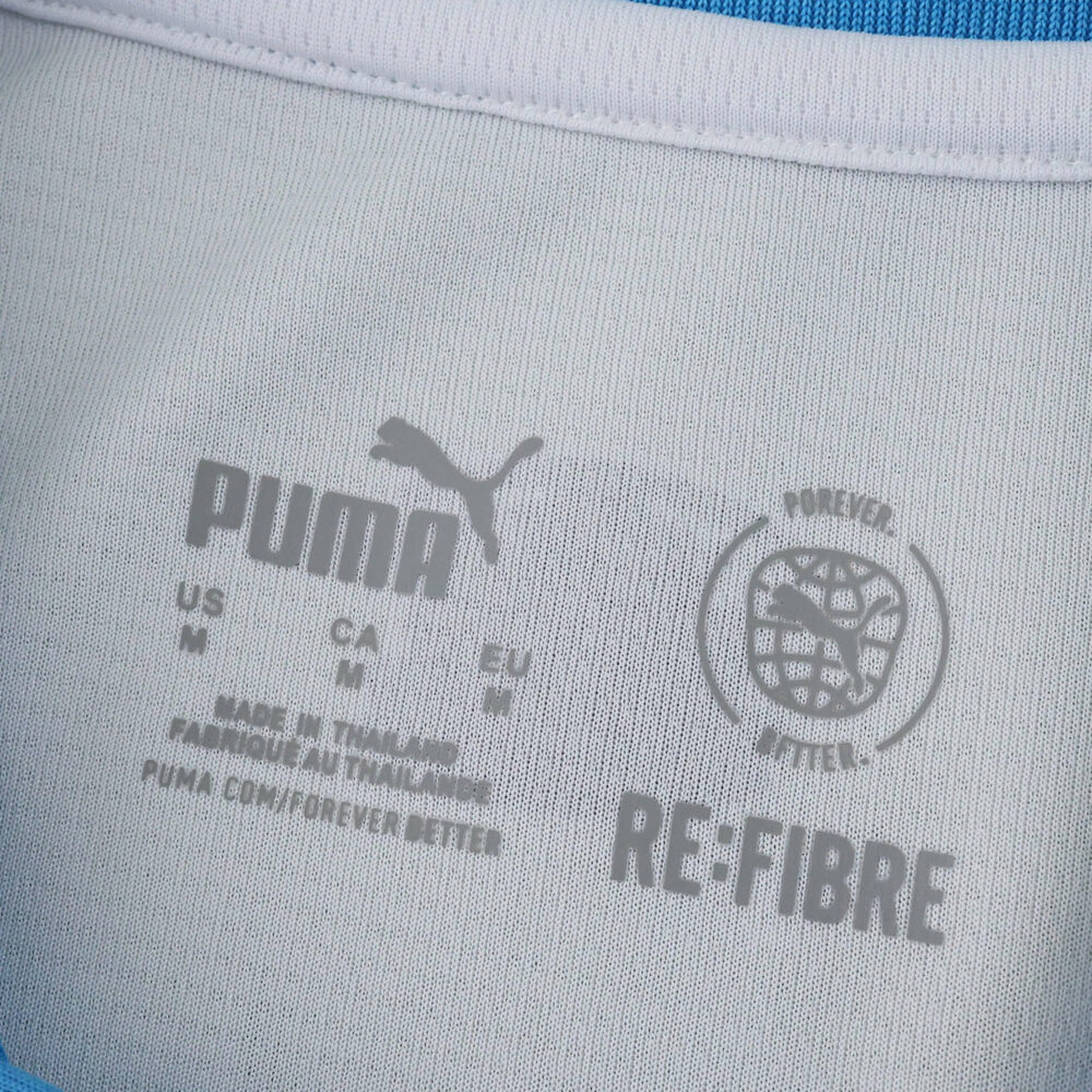 Close-up of Olympique Marseille 2025/26 Home Fan jersey collar with Puma and RE:FIBRE logos.