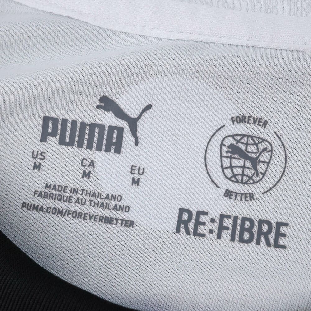 Close-up of the PSV Eindhoven 2025/26 home fan jersey's Puma label showing size and sustainability logos.