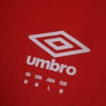 Close-up of the Umbro logo and size chart on the Rangers Third 2025/26 Fan Version jersey in red.