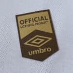 Gold and black Umbro "Official Licensed Product" badge on the Santos FC 2025/26 home jersey fabric.