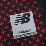 Close-up of the New Balance Authentic Licensed Product label on the Bayer Leverkusen 2025/26 Home Fan jersey.